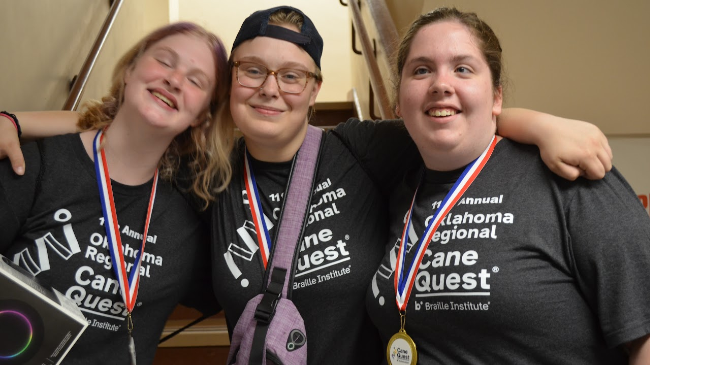 Three students wearing cane quest t-shirts with medals around neck