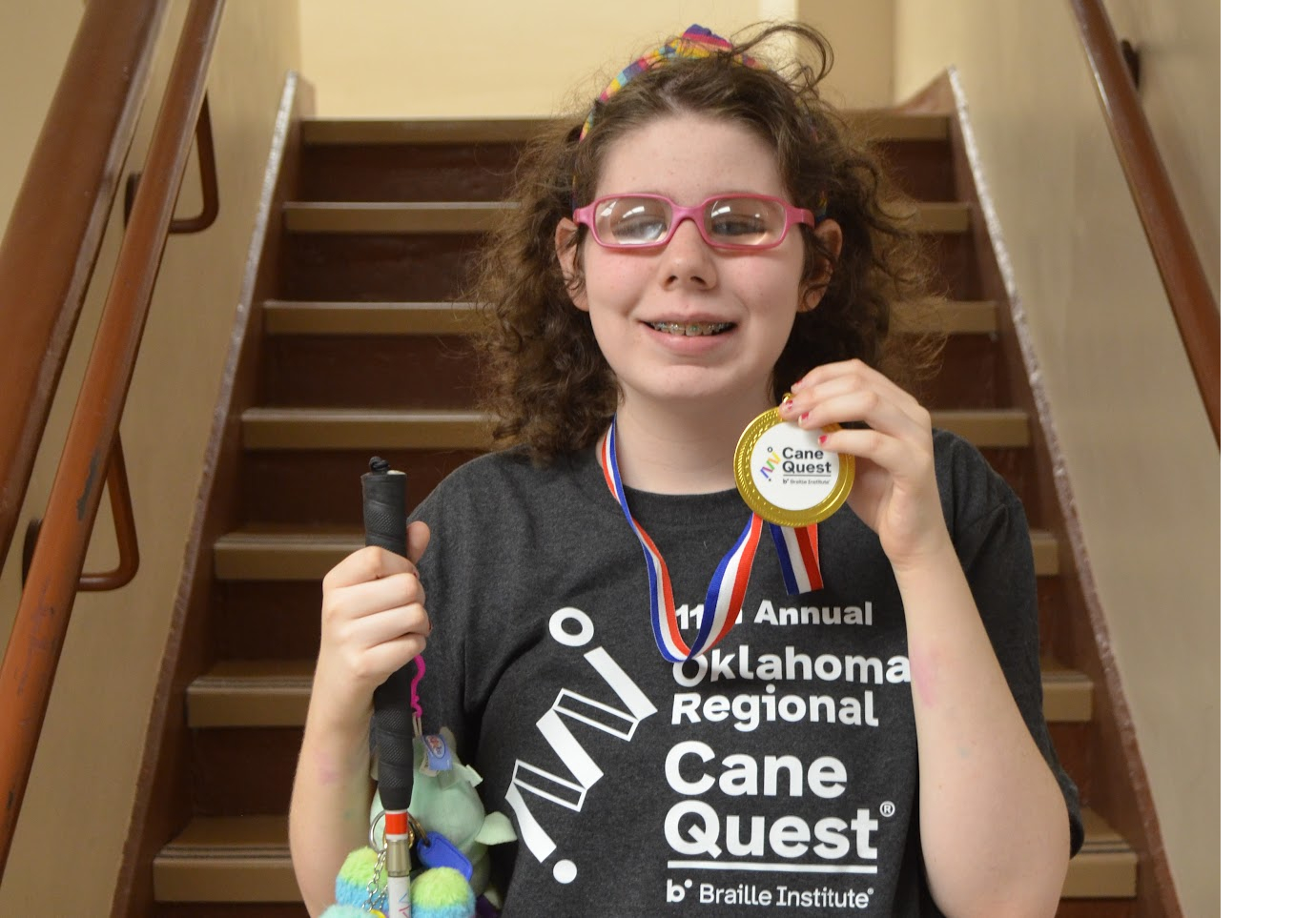 Student with cane and showing cane quest medal